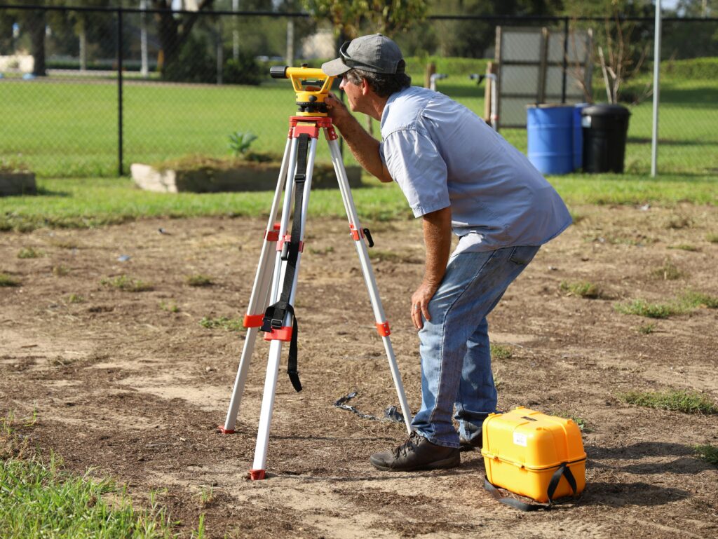 A specialist performs a site assessment using surveying equipment to know how deep a septic tank should be buried.