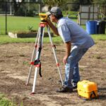 A specialist performs a site assessment using surveying equipment to know how deep a septic tank should be buried.